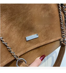 Detailaufnahme der karamellbraunen Umschlagtasche mit Silberkette und Metallbeschlägen