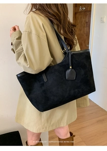 Gros plan d'un grand sac fourre-tout noir en daim avec un trench-coat de style rétro chic