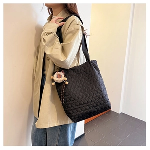 Detail of black quilted tote bag with diamond texture and cute lion plush charm