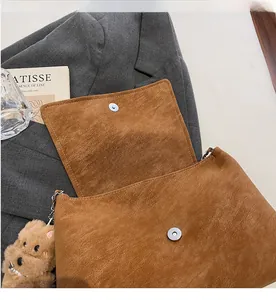 Detail der braunen Wildledertasche mit Magnetschnalle und süßem Plüsch-Hundeanhänger