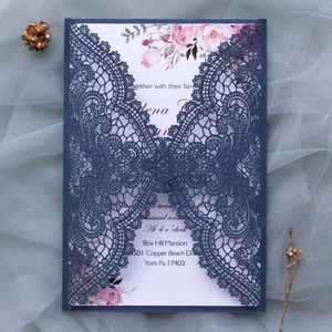 Macro detail of laser-cut navy blue lace pattern and watercolor floral wedding invite