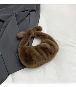 Detail shot of brown plush faux fur handbag with knotted handle and ruched design