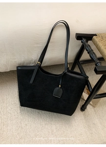 Detail of vintage suede tote bag showing black leather trim and golden metal buckles