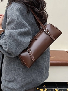 Fashionable dark brown cylindrical shoulder bag in glossy leather with silver buckle accents