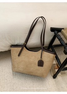 Close-up of khaki suede tote bag with brown leather trim and adjustable strap details