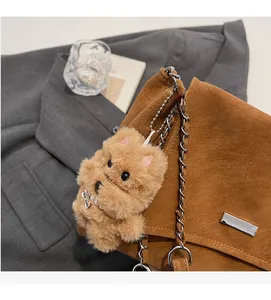 Detail eines flauschigen Welpenanhängers mit Perlenkette an einer braunen Kettentasche