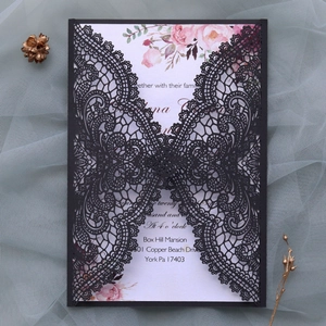 Close-up of laser-cut black lace wedding invitation with pink floral inner card