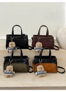 Dettaglio di quattro borse Kelly in pelle in vari colori con ciondoli a forma di orsetto
