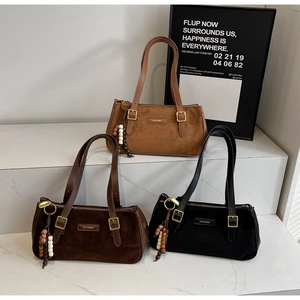 Detailed view of suede shoulder bags in brown and black with ethnic bead charms