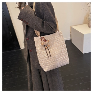 Dettaglio della borsa tote trapuntata beige con motivi a rombi e ciondolo a orsetto