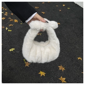 Dettaglio di una borsa in peluche bianca con manico annodato in morbida ecopelliccia