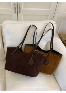 Detail of minimalist suede tote bags in coffee and brown on a white leather sofa