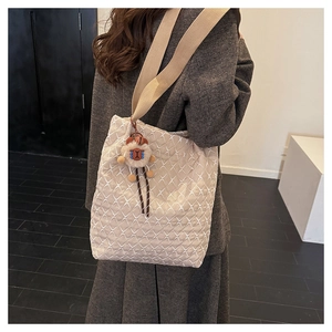 Detailed view of beige quilted tote bag with diamond pattern and plush deer charm pendant