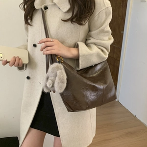 Brown leather crossbody hobo bag with cute plush rabbit charm on a model