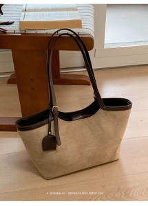 Minimalist beige suede tote bag with brown leather trim in a cozy home setting