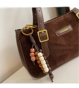 Detail of dark brown suede baguette bag with colorful ceramic bead and wood bead charm