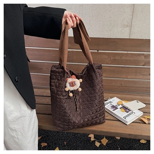 Quilted dark brown tote bag on wooden bench with autumn leaves and sheep charm