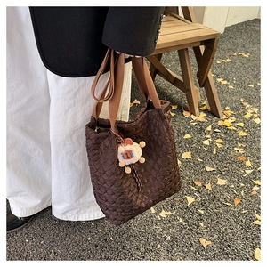 Close-up of brown quilted tote bag with cute plush sheep charm and wide shoulder strap