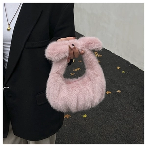 Close-up of fluffy pink faux fur handbag held by model wearing a black blazer jacket