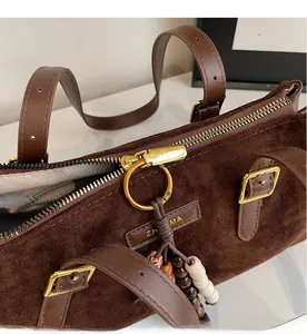 Detail of brown suede baguette bag with gold zipper and decorative wooden beads