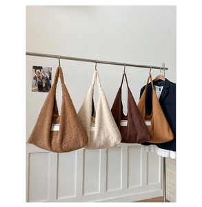 Multiple colors of plush lamb wool tote bags hanging on a display rack in a store