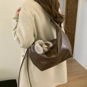 Detail of deep brown glossy PU leather tote bag with cute plush rabbit keychain accessory