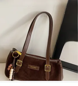 Detail of vintage brown baguette bag with suede texture and decorative beaded tassel