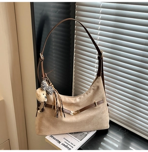 Detail of light tan faux suede shoulder bag with heart lock and trendy plush charms