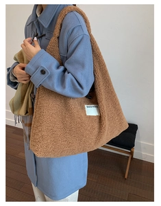 Detail of a large brown faux shearling tote bag with SEEYOU label on a shoulder strap