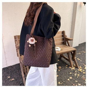 Quilted tote bag with lion charm detail shown in a minimalist autumn setting