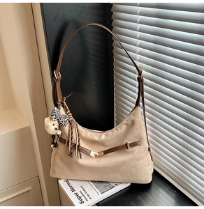 Detail view of beige suede shoulder bag with brown leather strap and plush bear charm