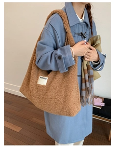 Detail of soft brown lamb wool tote bag with SEEYOU label worn with a blue coat