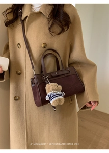 Dettaglio della borsa Kelly marrone retrò con ciondolo a orsetto su un cappotto autunnale