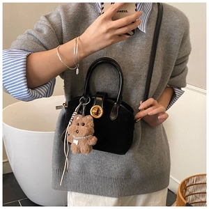 Chic black mini shell bag with gold hardware and a cute brown plush bear charm