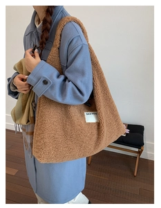 Close-up of brown faux shearling tote bag with SEEYOU label on light blue coat