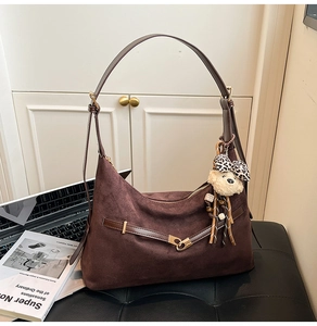 Close-up of brown matte dumpling bag with leather straps and leopard teddy bear charm