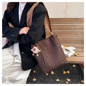 Close-up of quilted coffee tote bag with wide strap and cute sheep charm on park bench