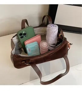 Top view of spacious brown baguette bag interior showing phone, wallet, and umbrella