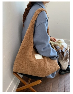 Close-up of brown faux shearling shoulder bag featuring a white square SEEYOU label