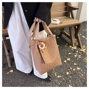 Detail of khaki quilted tote bag with diamond pattern and cute plush animal charm on strap