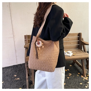 Detail of khaki quilted tote bag with lion plush pendant and diamond stitching