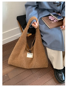 Detail of soft brown faux shearling tote bag featuring SEEYOU label and zipper closure