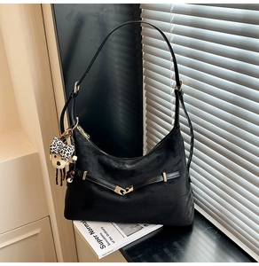 Close-up of black matte dumpling bag with decorative buckle and leopard bear charm
