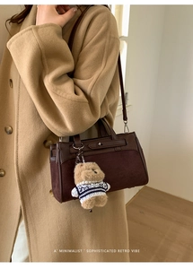Dettaglio borsa retrò in pelle e camoscio con un grazioso ciondolo a forma di orso