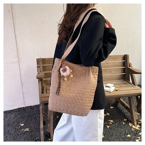 Detailed view of brown quilted tote bag with cute plush lion charm and wide shoulder strap