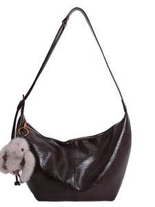 Dark brown high-gloss oil wax leather hobo bag with a plush bunny charm on white background