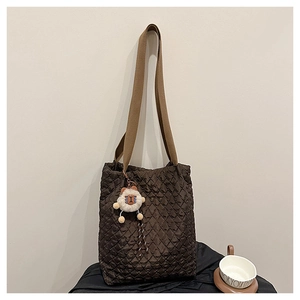 Detail view of quilted puffer tote bag in deep chocolate brown with sheep plush charm