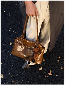 Dettaglio della borsa tote marrone scuro in vernice con peluche barboncino e cuore