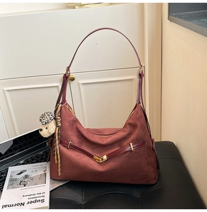 Detail of burgundy suede dumpling bag with leather straps and cute bear charm