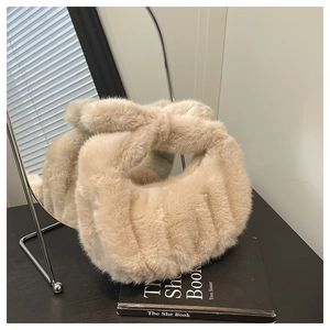 Dettaglio di una borsa beige in ecopelliccia con manico a nodo e trama a coste morbide